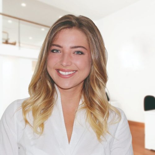 Eine lächelnde Frau, die ein Kontakt-Unternehmen vertritt, in einem weißen Hemd steht in einem Büro.